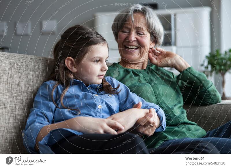 Grandmother and her granddaughter sitting together on the couch at home caucasian caucasian ethnicity caucasian appearance european grandmother grandmas