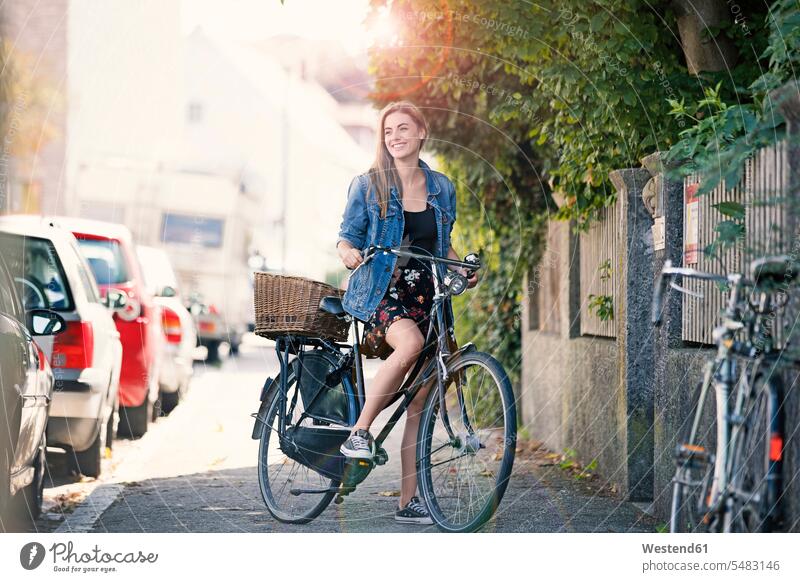 Young woan with bicycle in the city bikes bicycles young women young woman denim jacket jeans jackets riding bicycle riding bike bike riding cycling bicycling