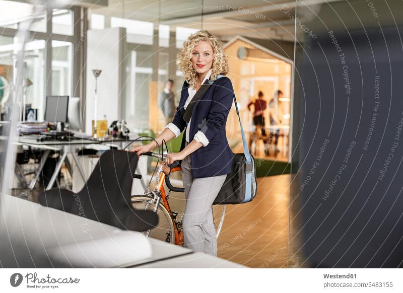 Portrait of woman with bicycle in office bikes bicycles offices office room office rooms businesswoman businesswomen business woman business women workplace
