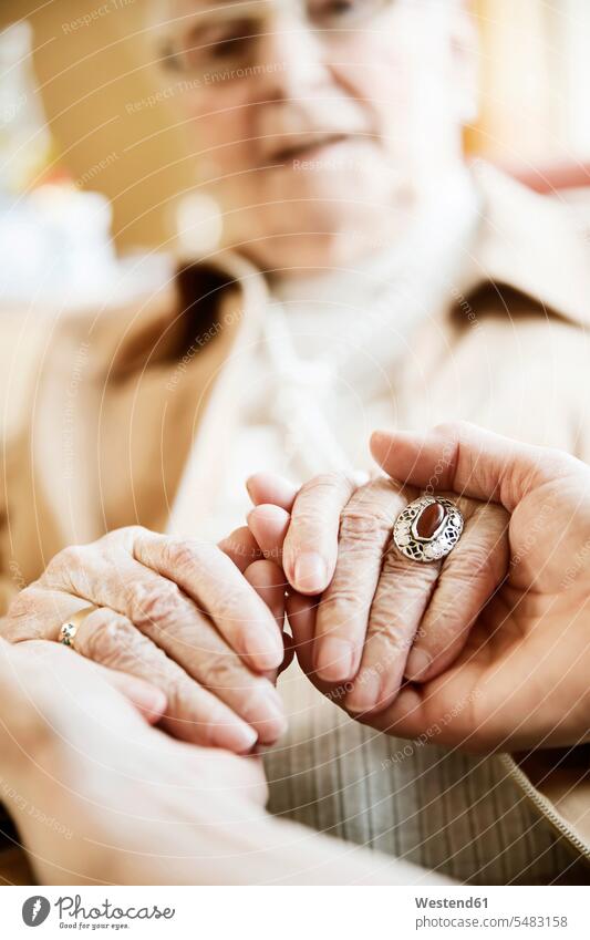 Adult daughter holding hands of her mother with Alzheimer's disease, close-up ring rings bonding candid candid shot age sunset years evening of life assistance