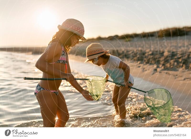 Spain, Menorca, two girls with dip nets on the beach sister sisters playing scoop nets landing net beaches females siblings brother and sister