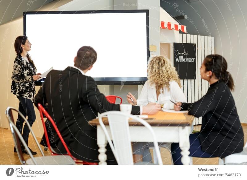 Woman leading presentation in office at large screen business people businesspeople presentations screens monitor monitors workshop businesswoman businesswomen