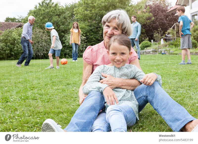 Portrait of happy grandmother with granddaughter and family in background portrait portraits families smiling smile garden gardens domestic garden happiness