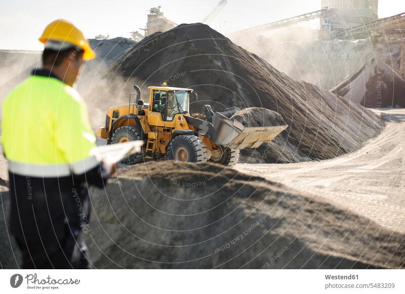 Worker standing at quarry, using clipboard working At Work mining gravel pit open-pit mining surface mine surface mining strip mining Open-Pit Mine