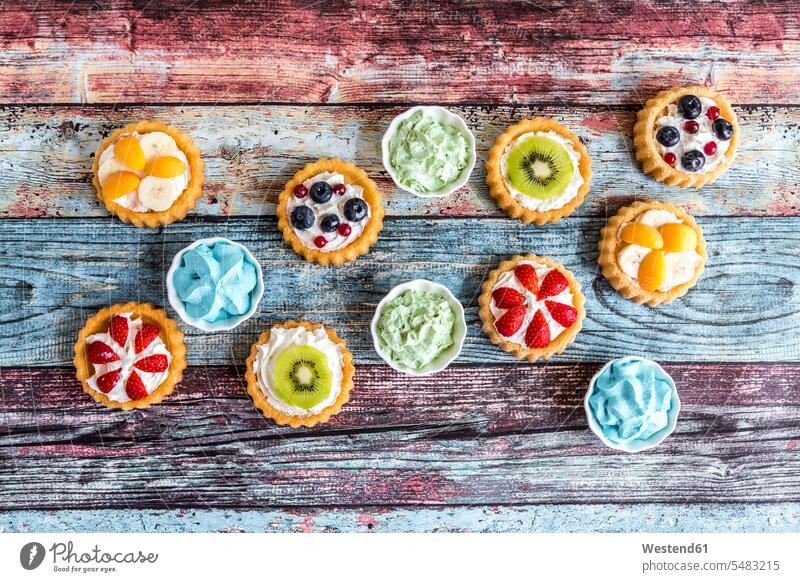 Mini pies with whipped cream garnished with different fruits still life still-lifes still lifes circle circles circular decorated tartlet tasty savoury yummy