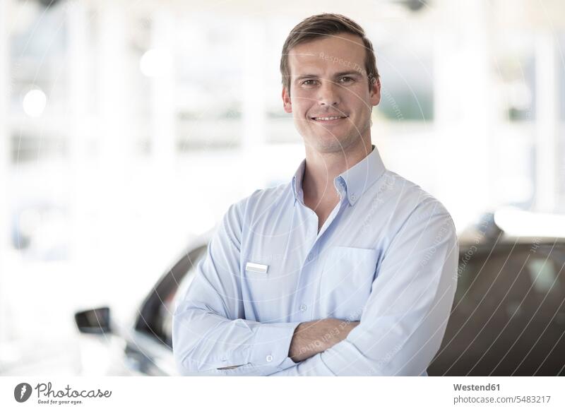 Portrait of confident car dealer in showroom car dealership car dealerships automobile Auto cars motorcars Automobiles smiling smile trade trading motor vehicle