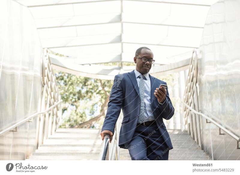 Businessman checking cell phone on stairs mobile phone mobiles mobile phones Cellphone cell phones portrait portraits Business man Businessmen Business men