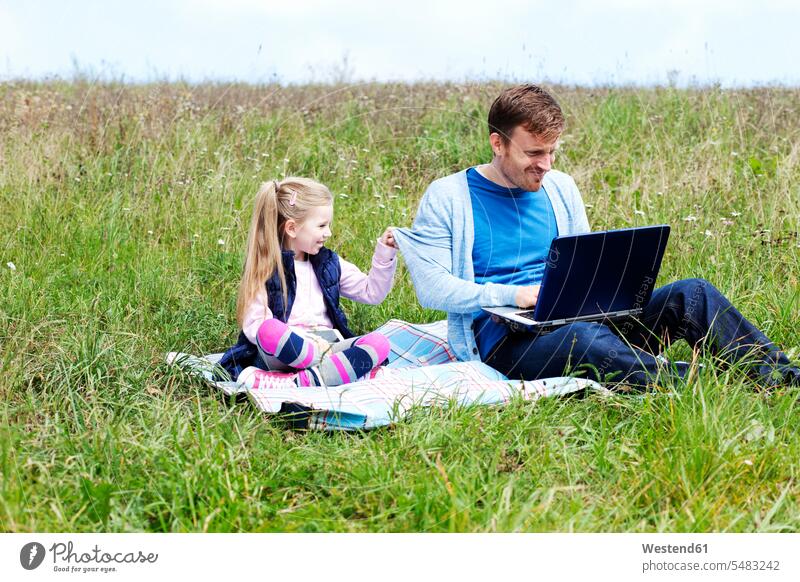 Father and daughter sitting on meadow, smartphone and laptop caucasian caucasian ethnicity caucasian appearance european Mobility mobile technology technologies