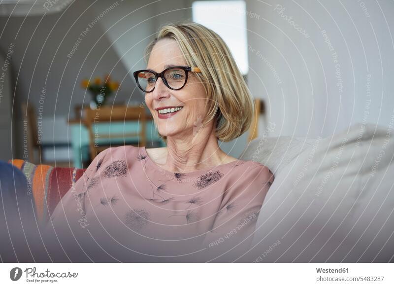 Smiling mature woman at home on the sofa relaxed relaxation smiling smile sitting Seated females women relaxing Adults grown-ups grownups adult people persons
