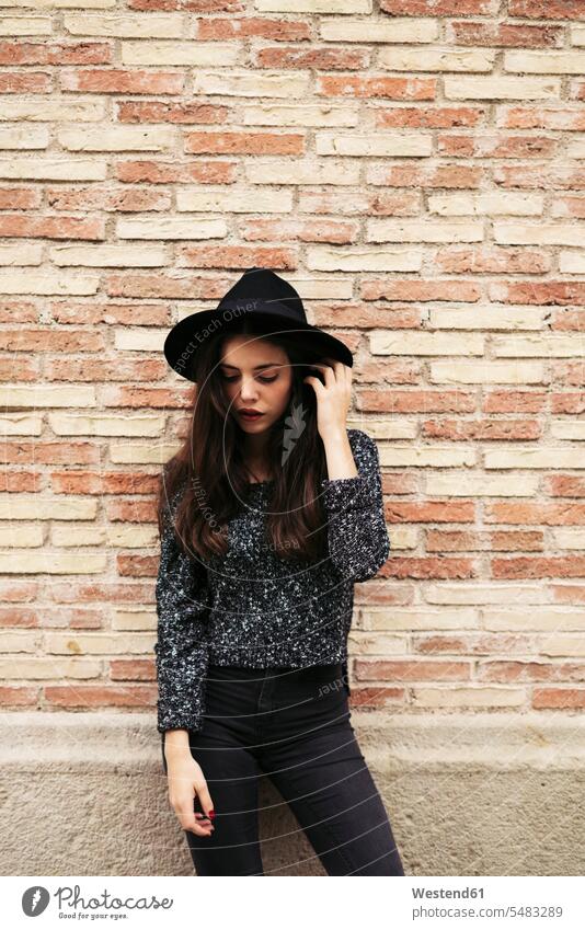 Fashionable young woman wearing black hat standing in front of facade fashionable females women Adults grown-ups grownups adult people persons human being