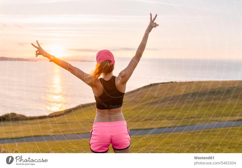 Young woman looking at the sea after workout with arms out exercising exercise training practising females women Adults grown-ups grownups adult people persons