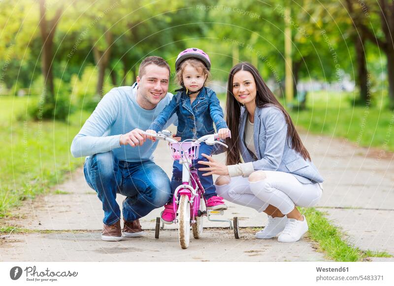 Smiling parents with daughter on bike mother mommy mothers ma mummy mama family families riding daughters smiling smile bicycle bikes bicycles father fathers