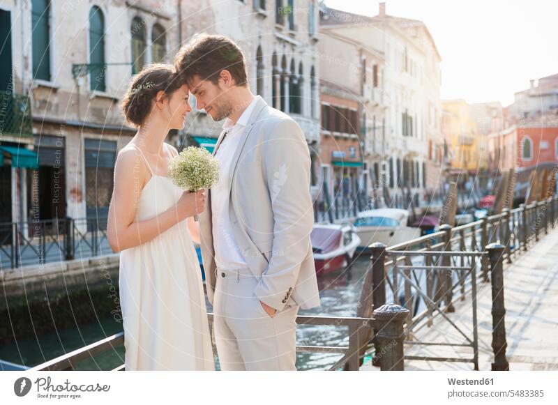 Italy, Venice, bridal couple standing head to head in front of canal bridal couples married couple married couples marriage people persons human being humans