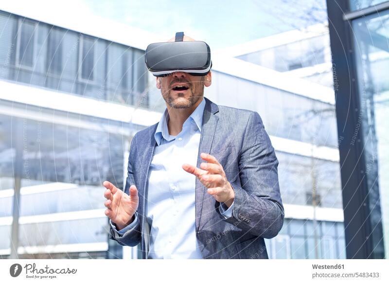 Man wearing virtual reality glasses outdoors VR senses gripping grabbing reaching waist up Waist-Up upper body upper part shot astonished puzzled wonder