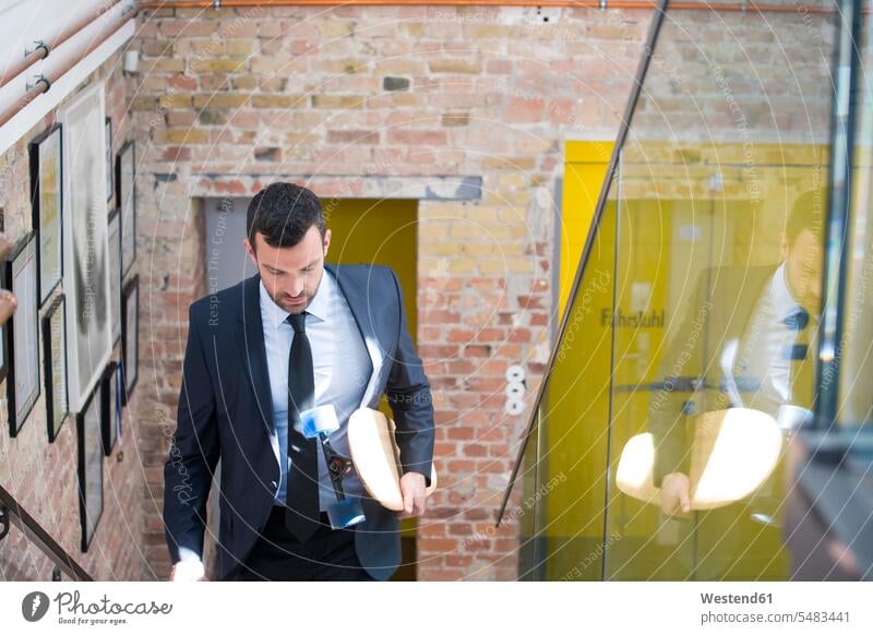 Young businessman in a suit carrying longboard, climbing stairs caucasian caucasian ethnicity caucasian appearance european Mobility mobile Longboard