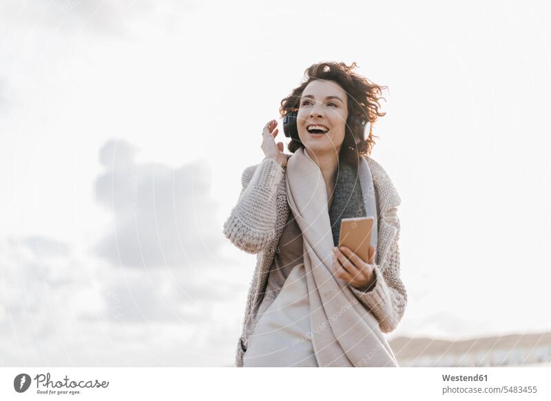 Happy woman on the beach with cell phone and headphones headset mobile phone mobiles mobile phones Cellphone cell phones beaches females women laughing Laughter