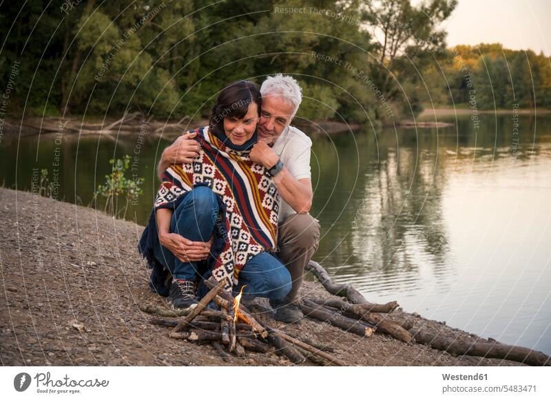 Senior couple at campfire at a lake relaxed relaxation happiness happy Camp Fire Campfire Bonfire twosomes partnership couples lakes senior men senior man