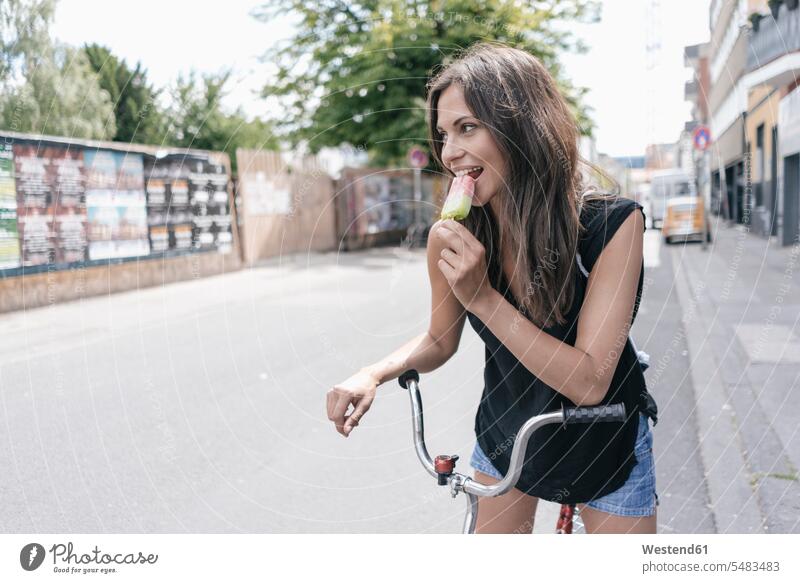 Woman with bicycle eating ice lolly woman females women portrait portraits smiling smile Adults grown-ups grownups adult people persons human being humans