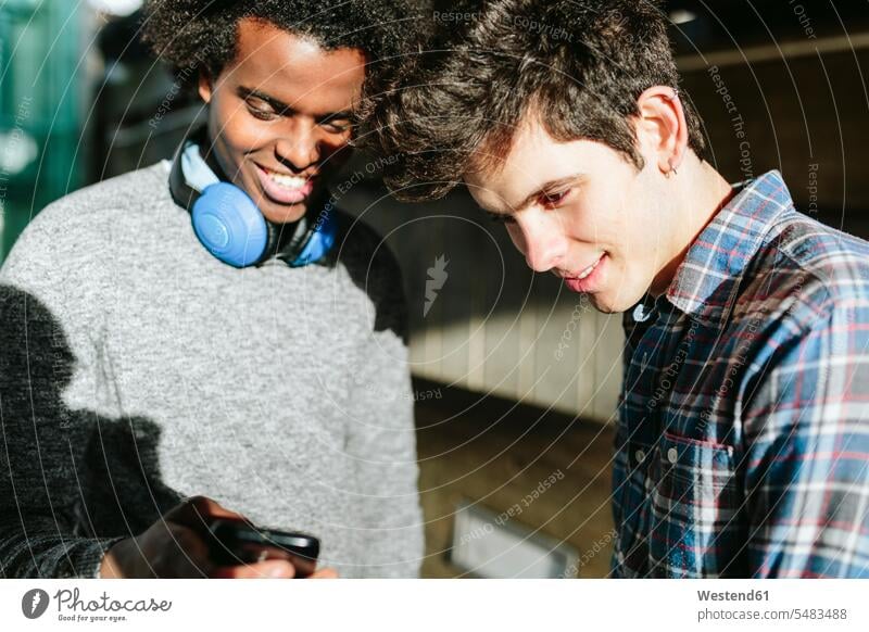 UK, London, two young man looking at theit smartphones Afro European Ethnicity student students outdoors outdoor shots location shot location shots friendship