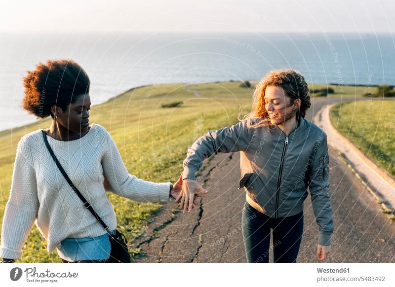Two best friends holding hands walking at the coast happiness happy smiling smile woman females women female friends Adults grown-ups grownups adult people