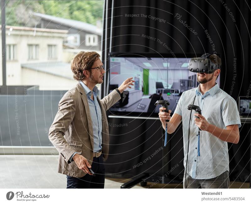 Man talking to colleague wearing VR glasses in front of screen specs Eye Glasses spectacles Eyeglasses colleagues screens monitor monitors virtual reality man