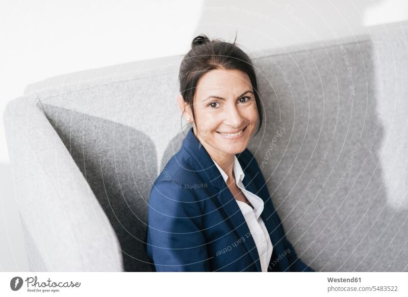 Portrait of smiling businesswoman on a couch businesswomen business woman business women portrait portraits females business people businesspeople