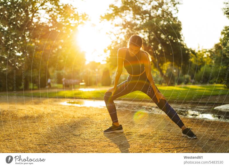 Sportive young woman stretching in park at sunset females women athlete sportswoman athletes female athlete sportswomen female athletes Adults grown-ups