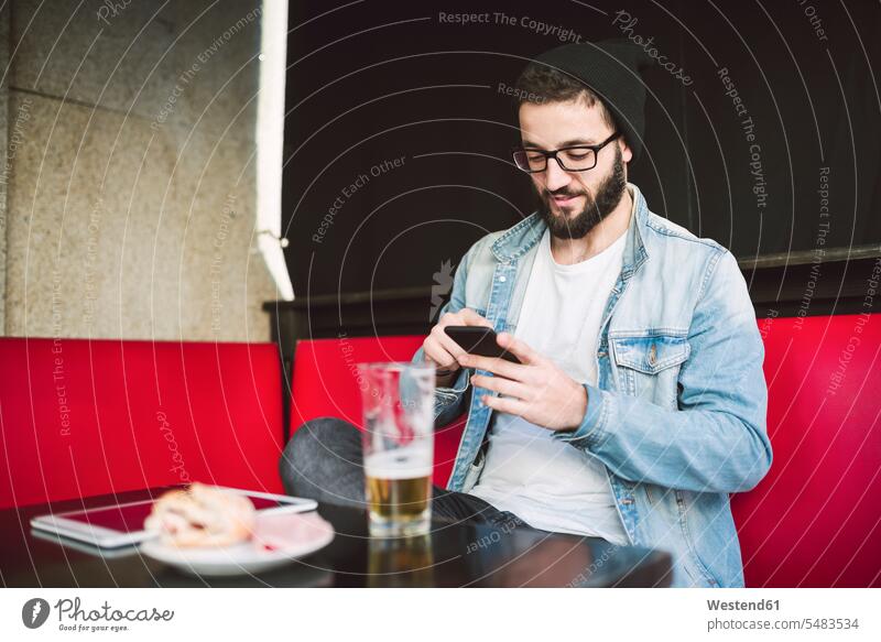 Young man sitting in a pub checking messages pubs tavern taverns Smartphone iPhone Smartphones men males mobile phone mobiles mobile phones Cellphone cell phone