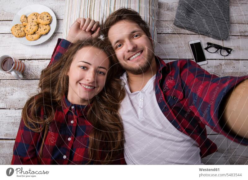 Portrait of young couple lying on the floor taking a selfie wooden brown hair brown haired brown-haired brunette Plate dish dishes Plates relaxation relaxing