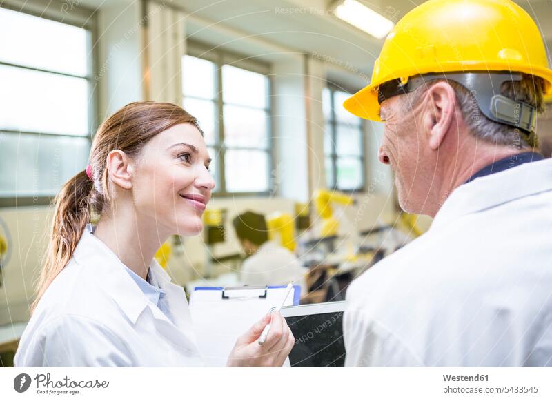 Two smiling engineers in factory talking speaking factories colleagues smile technology technologies engineering industry industrial examination examine