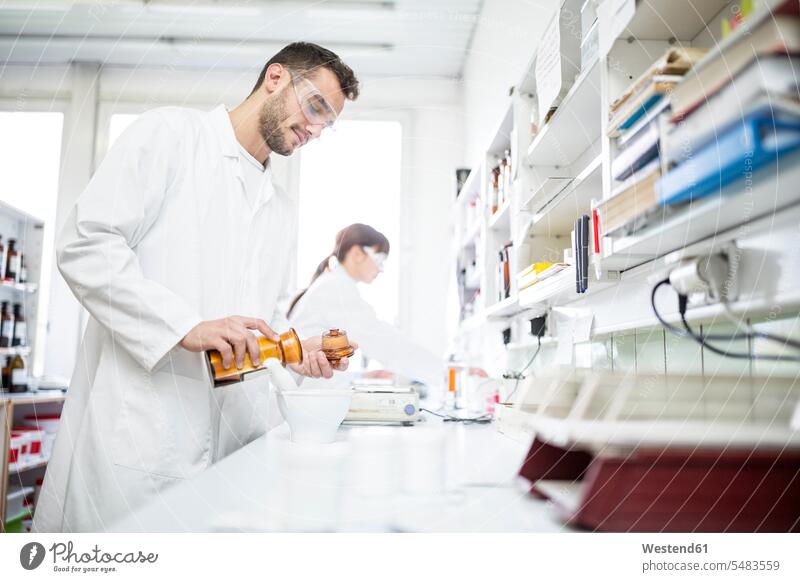 Man and woman working in laboratory of a pharmacy females women At Work Apothecary drugstores pharmacies Adults grown-ups grownups adult people persons