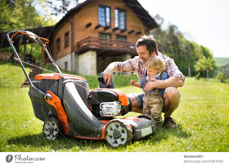 Father with his little son and lawn mower lawnmower garden gardens domestic garden sons manchild manchildren father pa fathers daddy dads papa family families