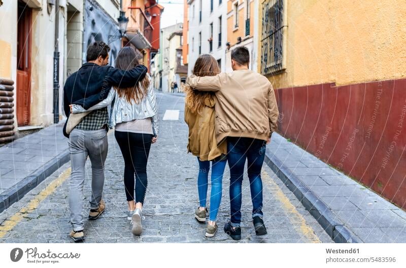 Two couples strolling in the city embracing embrace Embracement hug hugging friends walking going twosomes partnership town cities towns friendship people