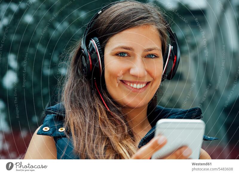 Portrait of smiling young woman with headphones and cell phone in the city smile music mobile phone mobiles mobile phones Cellphone cell phones females women