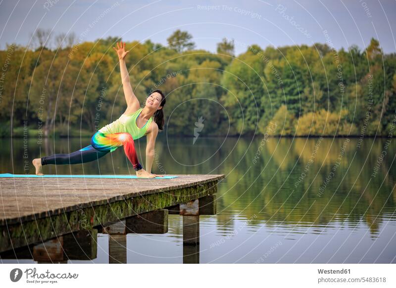 Woman practicing yoga on jetty at a lake lakes exercise exercises Yoga jetties woman females women water waters body of water Adults grown-ups grownups adult