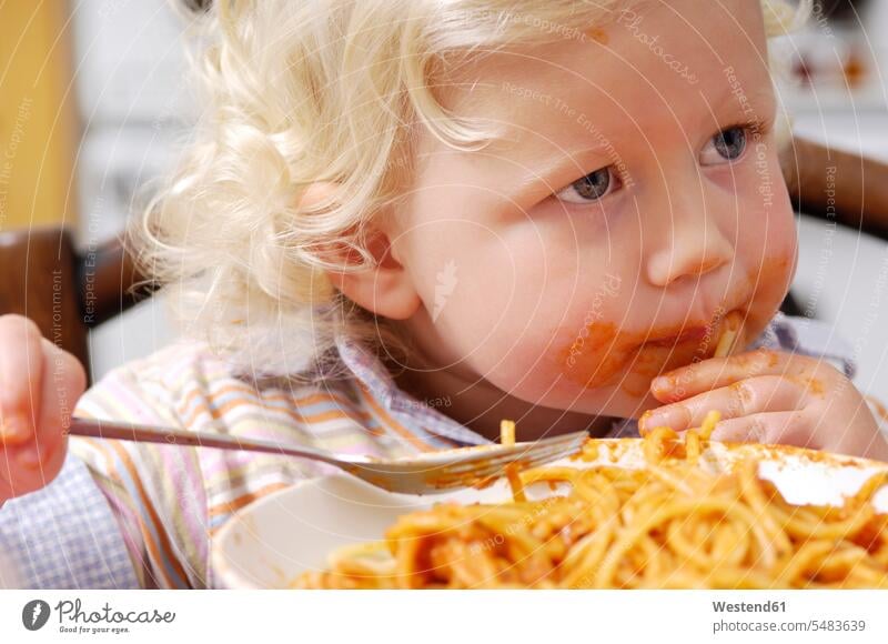 Portrait of little blond girl eating spaghetti with tomato sauce Plate dish dishes Plates messy looking sideways sideways glance Sideway Glance side glance