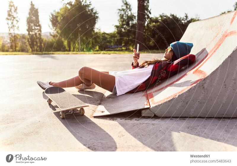 Young woman with skateboard and cell phone in a skatepark relaxed relaxation Skate Board skateboards lying laying down lie lying down mobile phone mobiles