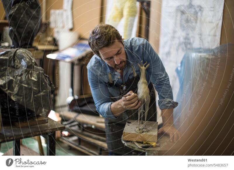 Sculptor working in studio on animal figurine workshop studios man men males At Work craft crafts handwork handcraft hand work manual labour manual work