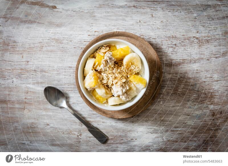 Bowl of granola with oat flakes, natural yoghurt, ananas and banana overhead view from above top view Overhead Overhead Shot View From Above wooden plate