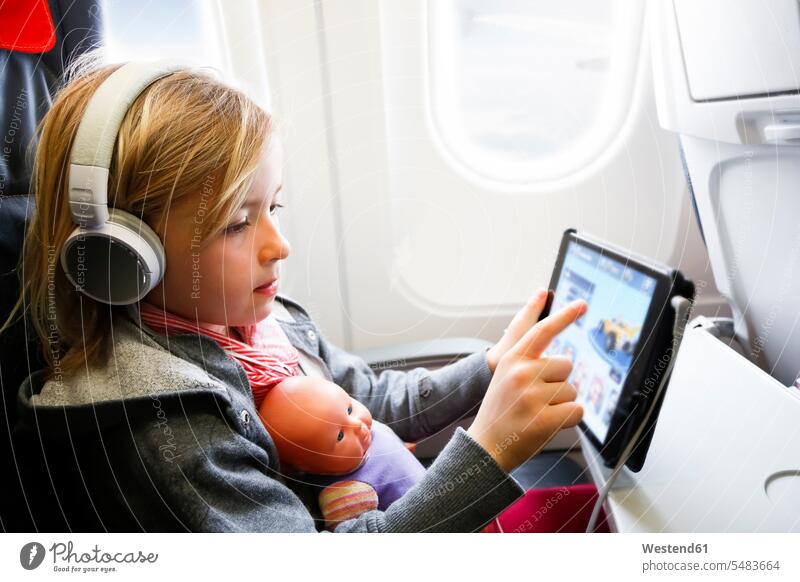 Little girl sitting on an airplane watching something on digital tablet aeroplanes airplanes females girls digitizer Tablet Computer Tablet PC Tablet Computers