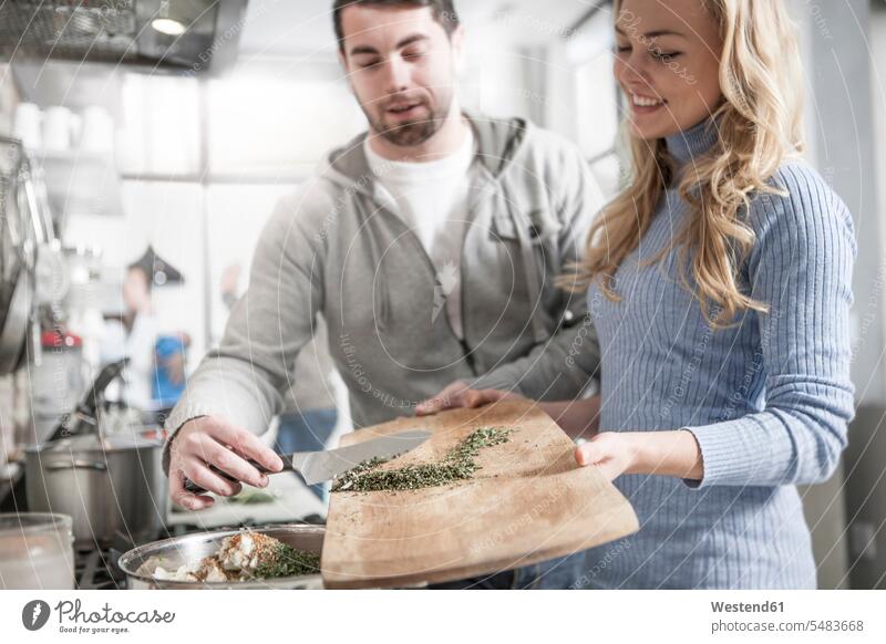 Couple helping one another moving spices in pot kitchen domestic kitchen kitchens cooking couple twosomes partnership couples people persons human being humans