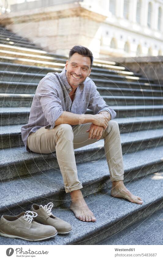 Portrait of smiling mature man sitting barefoot on stairs men males portrait portraits Adults grown-ups grownups adult people persons human being humans