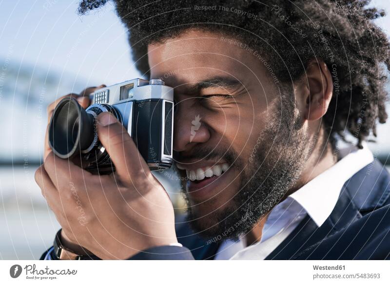 Close-up of smiling man taking a picture with a vintage camera men males photographing smile cameras Adults grown-ups grownups adult people persons human being