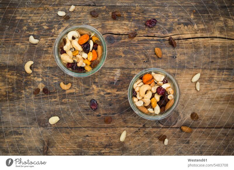 Two glasses of trail mix on dark wood Glass Glasses variation wooden rustic large group of objects many objects munchies nibbles raisin raisins corn maize