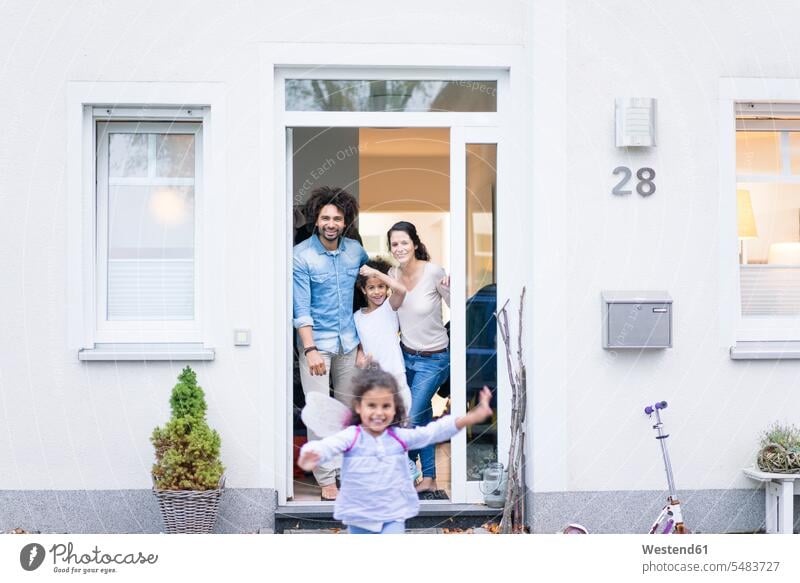 Laughing family waiting at the entrance of their home families home ownership private owned home standing welcome entrance door entry door entrance doors people