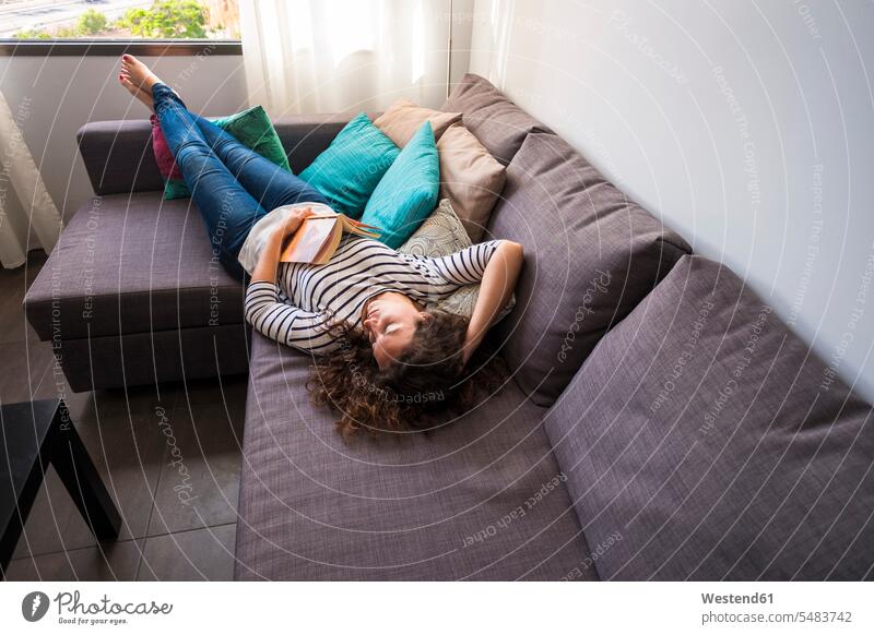 Woman relaxing on couch settee sofa sofas couches settees lying laying down lie lying down woman females women Adults grown-ups grownups adult people persons