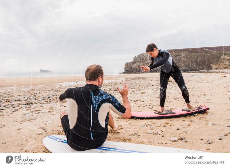 France, Bretagne, Crozon peninsula, man teaching woman surfing on beach surfboard surfboards beaches learning surfer surfers couple twosomes partnership couples