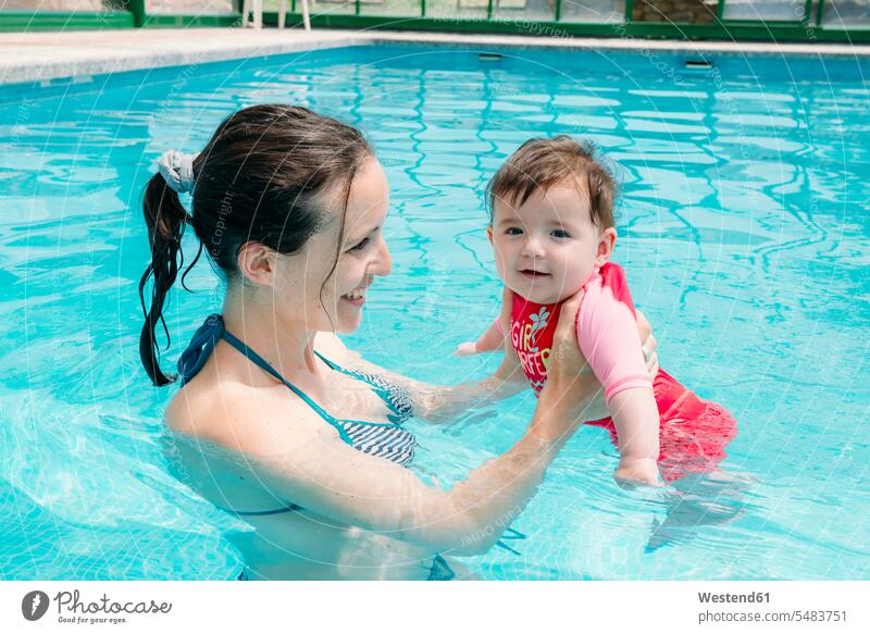 Cute baby girl learning to swim in the pool with her mother smiling smile infants nurselings babies mommy mothers ma mummy mama swimming pool pools