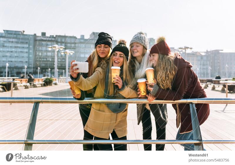 Four friends with coffee to go taking a selfie with smartphone mate female friend Selfies photograph smile Alimentation food Food and Drinks Nutrition Beverage