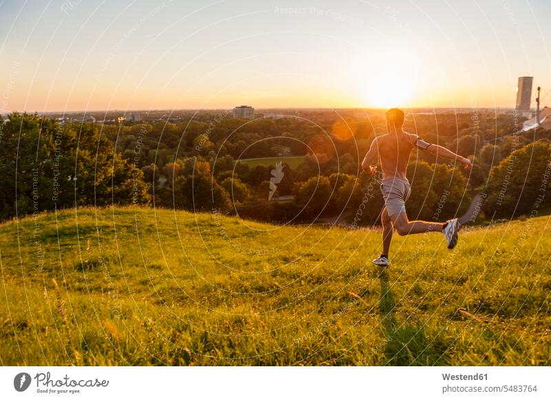 Barechested man running on meadow in park at sunset men males Jogging Adults grown-ups grownups adult people persons human being humans human beings fitness